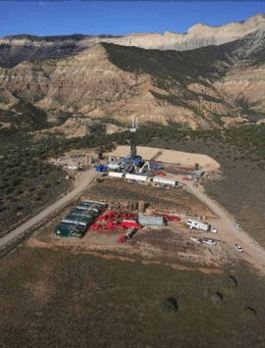 photo of natural gas well drilling operation against mountains